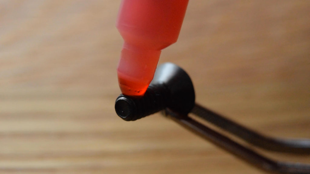 Liquid threadlocker (loctite) being applied to a small screw held in tweezers.