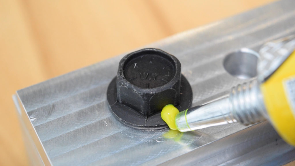 A fluorescent yellow marking material being applied across a screw head and workpiece.